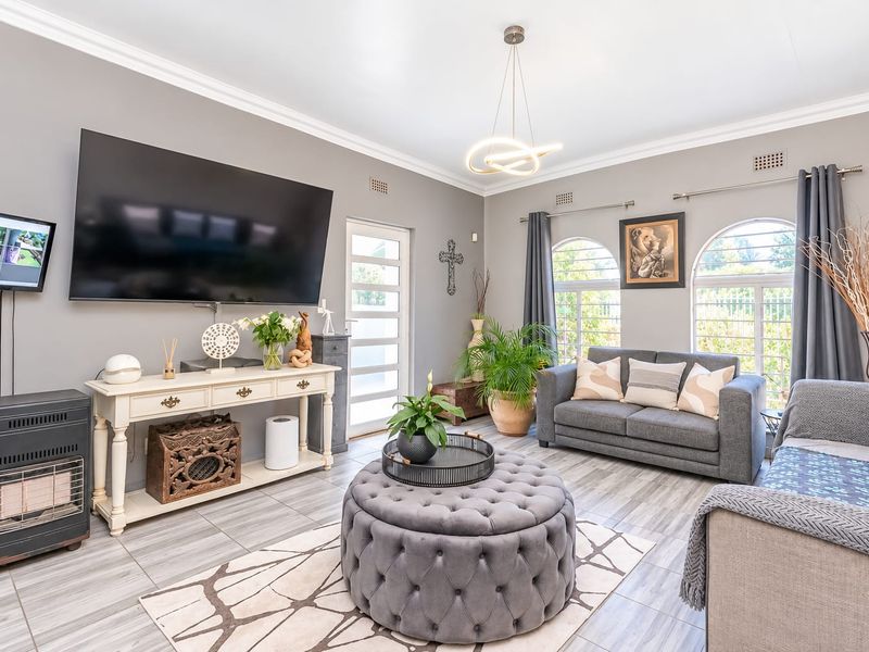 A well-maintained living room featuring tiled flooring, elegant arch windows, and modern lighting, creating a bright and comfortable space.