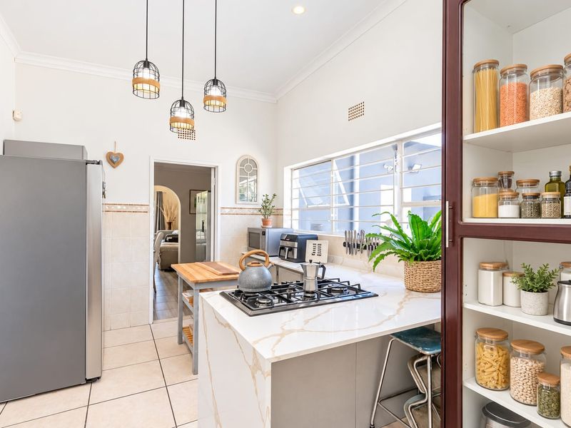 Modern kitchen featuring a gas hob, stone countertops, and a built-in pantry cupboard, offering a functional and well-maintained cooking space.