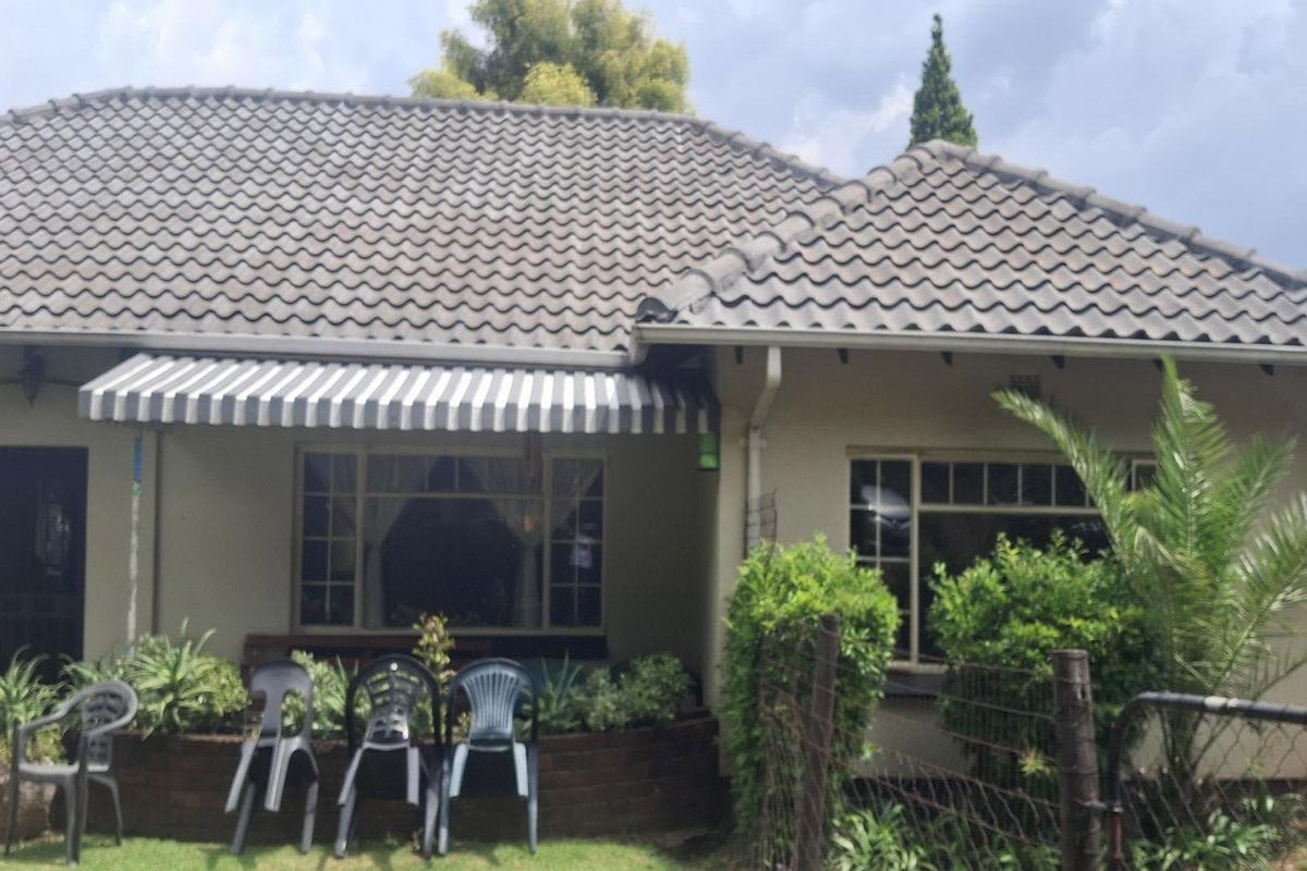 Rear view of the house featuring a tiled roof, exterior wall finish, and a retractable striped awning over the window area.