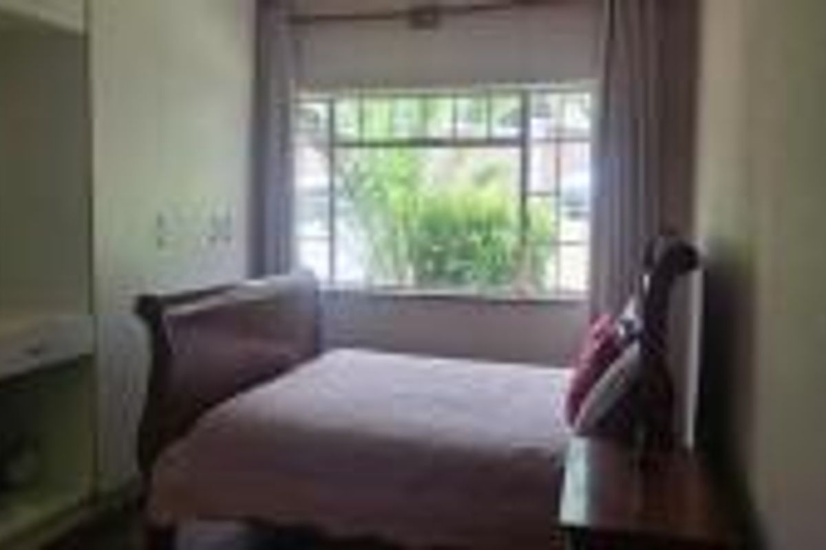 A bedroom featuring built-in cabinetry and a large window providing natural light.