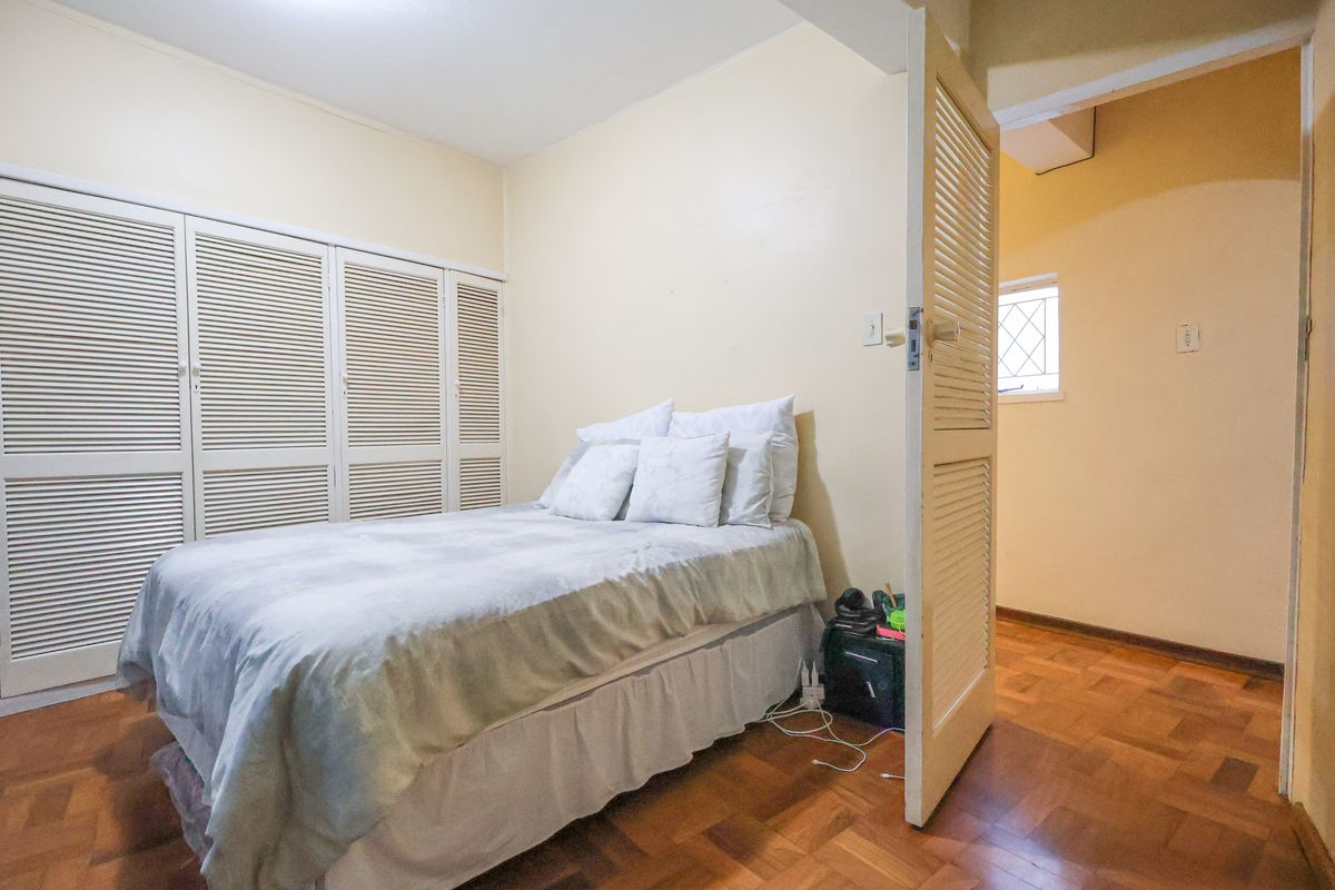 A bedroom featuring built-in louvered closet doors and parquet flooring, with an open doorway leading to an adjacent space.