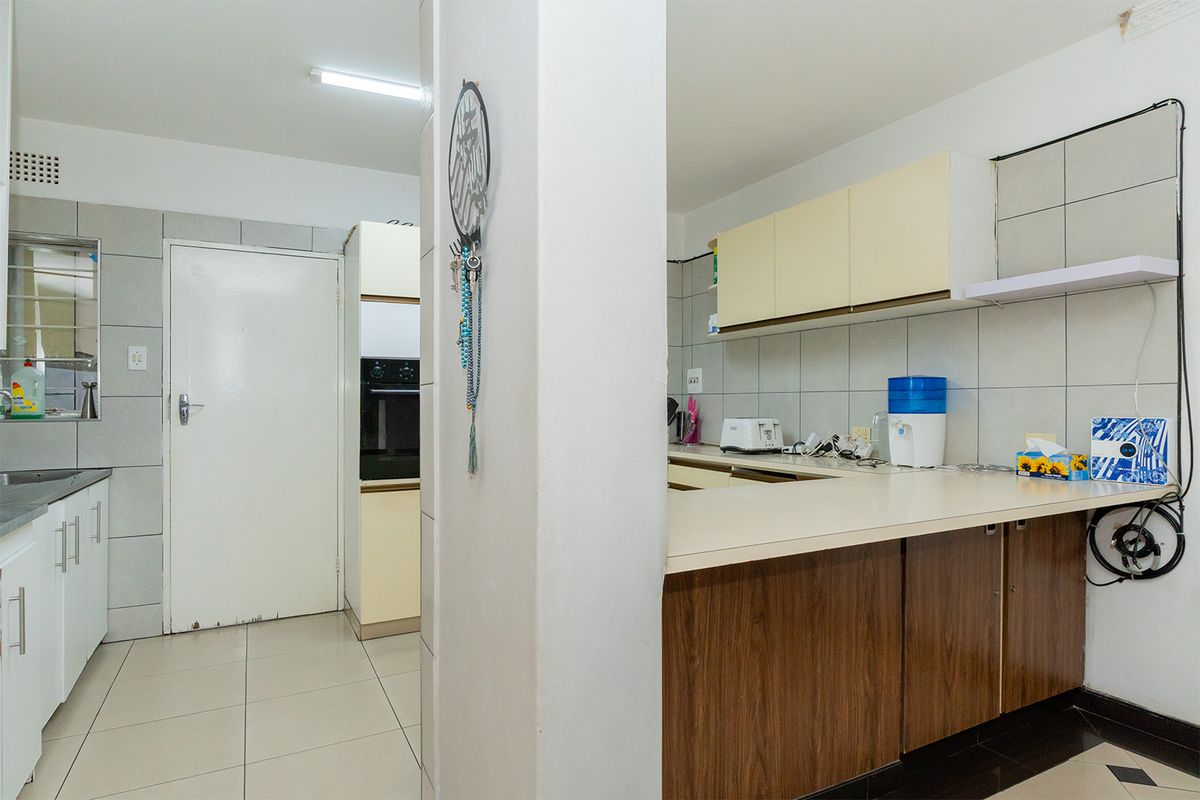 A functional kitchen featuring built-in cabinetry, laminate countertops, a tiled backsplash, and a built-in oven, offering a practical layout for daily meal preparation.