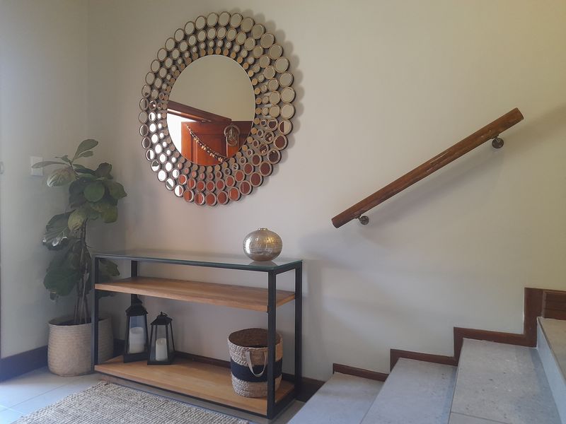 A welcoming entrance hall featuring a staircase with a wooden handrail and neutral tiled flooring.