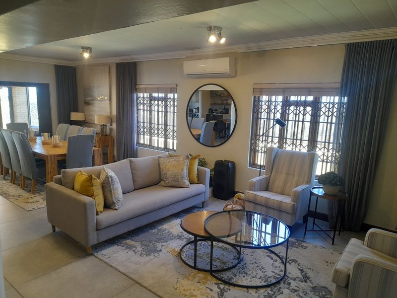 Spacious open-plan living and dining area featuring tiled floors, air conditioning, and large windows with security gates, creating a bright and functional living space.