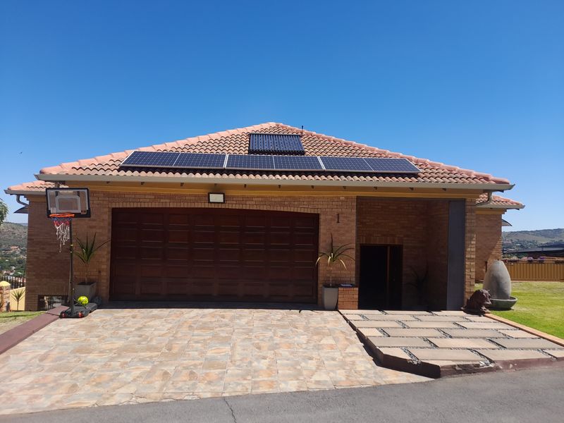 Front elevation of a cluster home featuring a brick facade, tiled roof with integrated solar panels, and a paved driveway leading to the garage.