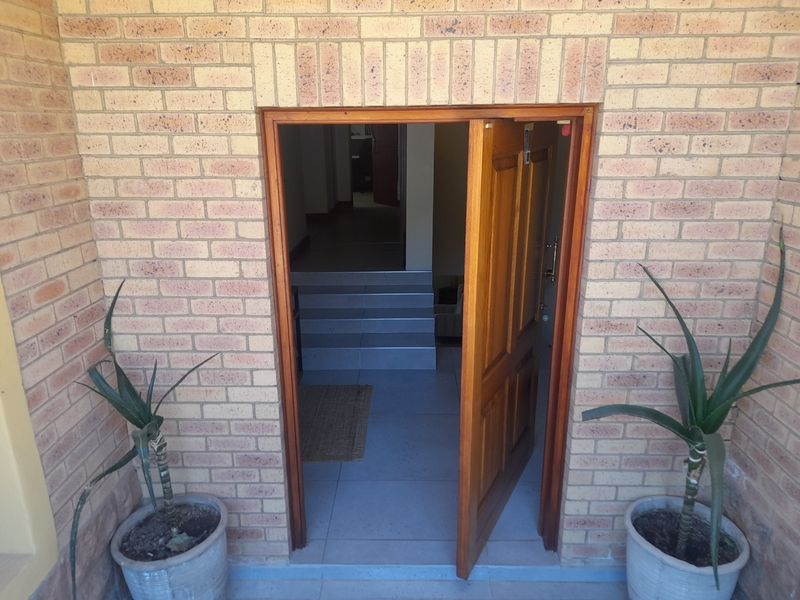 Entrance area featuring a face brick facade and a solid timber door leading into a tiled interior with steps.