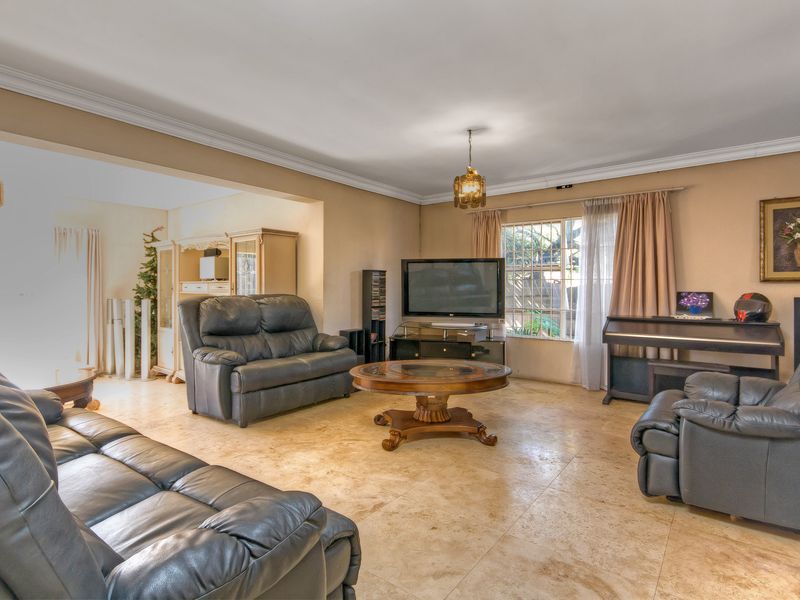 Spacious living room featuring neutral tiled flooring and classic cove cornicing, offering a comfortable and functional layout for relaxation.