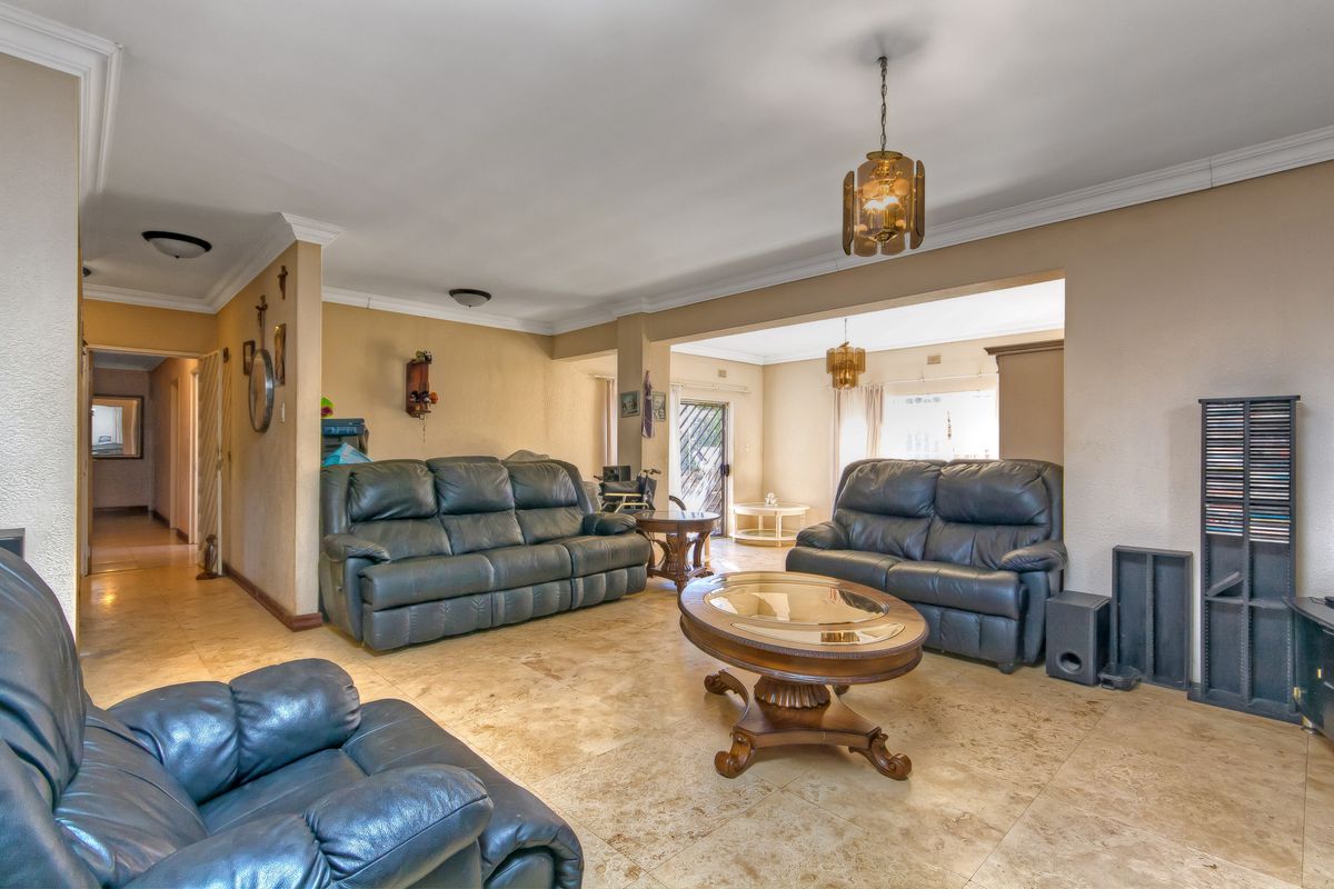 Spacious open-plan living area featuring neutral tiled flooring, crown molding, and integrated lighting, offering a versatile layout for comfortable family living.