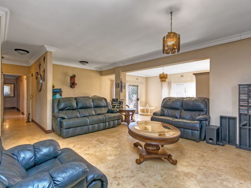 Spacious open-plan living area featuring neutral tiled flooring, crown molding, and integrated lighting, offering a versatile layout for comfortable family living.