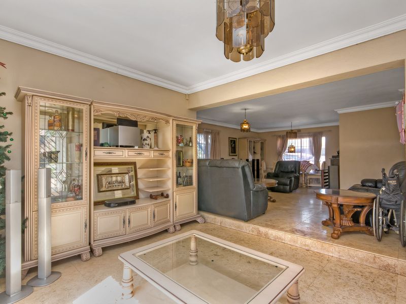 Spacious open-plan living area featuring stone tile flooring, a sunken lounge section, and decorative ceiling molding throughout the connected living spaces.