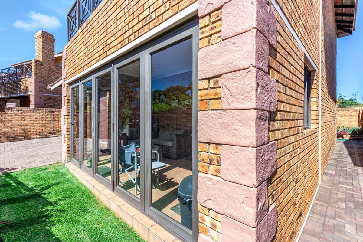 Exterior view of the townhouse featuring face-brick facade, stone corner detailing, and large aluminium-framed folding glass doors leading to the interior living space.