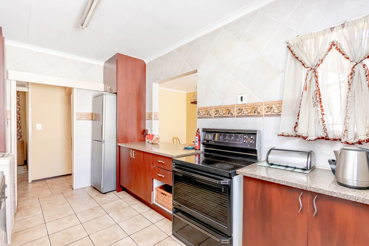 A functional kitchen featuring wood-finish cabinetry, tiled flooring, and a built-in stove with an oven, offering a practical layout for daily meal preparation.
