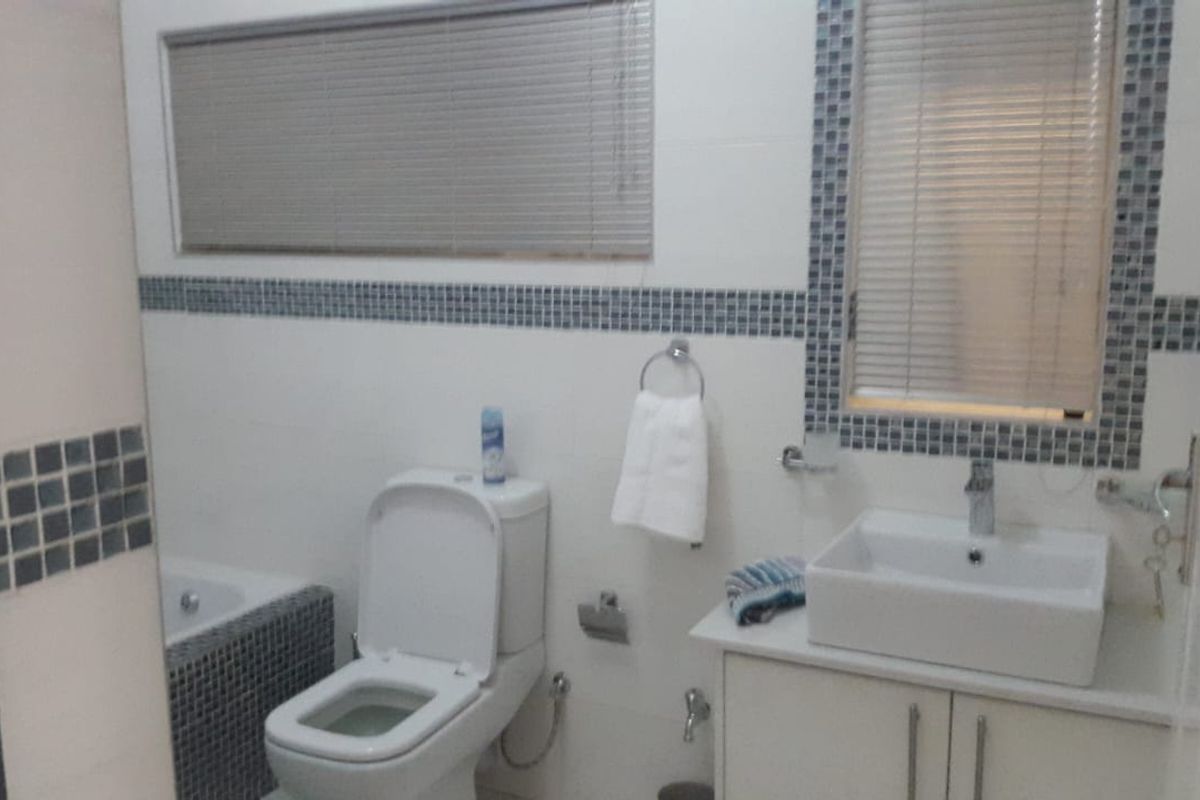 A functional bathroom featuring a modern vessel sink vanity, a standard toilet, and a tiled bathtub surround with mosaic decorative accents.