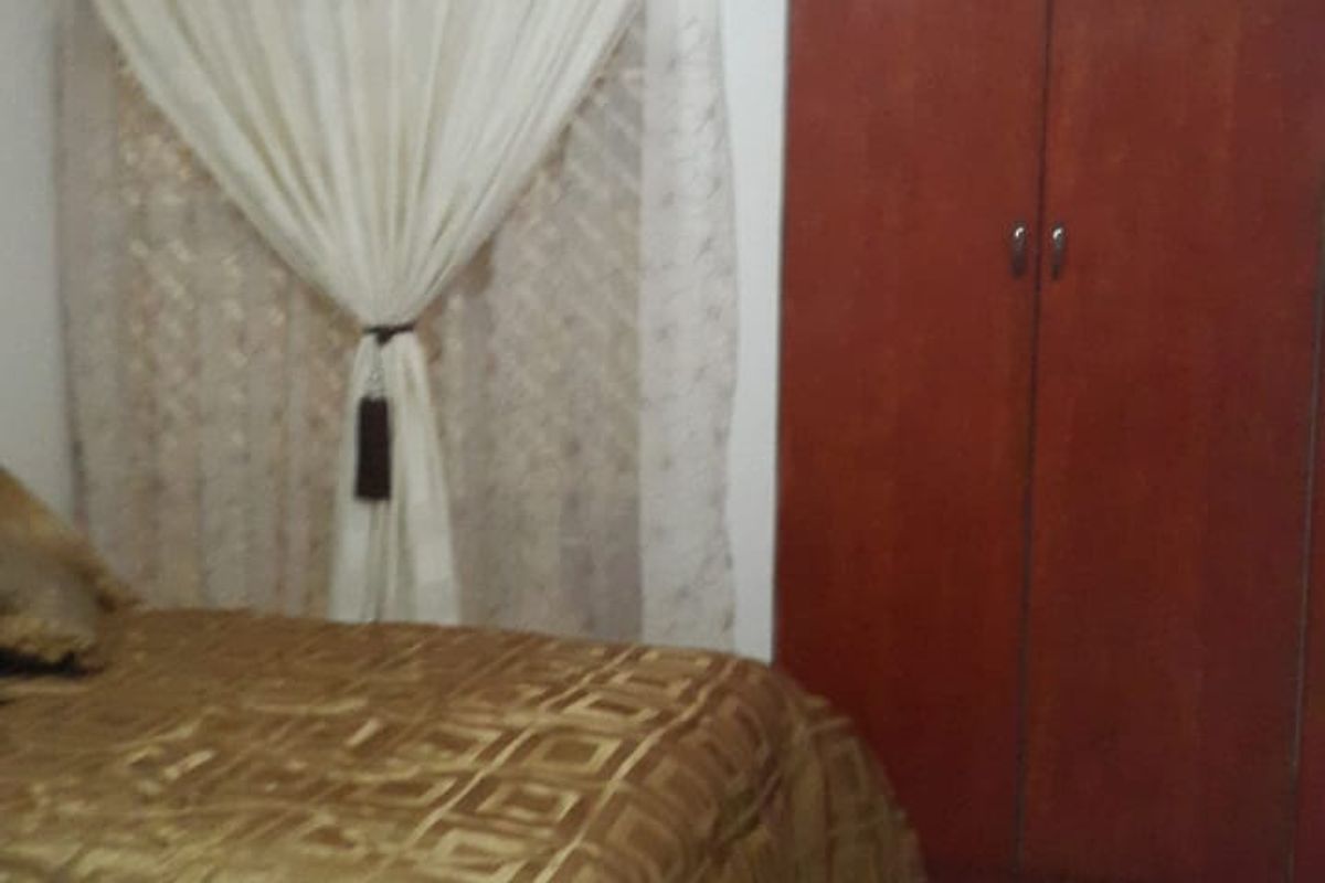 A bedroom featuring built-in wooden cupboards and tiled flooring.