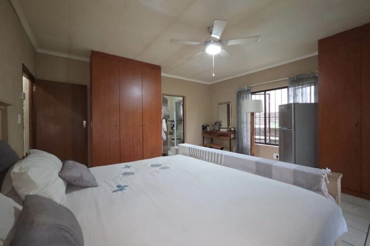 A spacious bedroom featuring built-in wooden cupboards, tiled flooring, and an en-suite bathroom access.