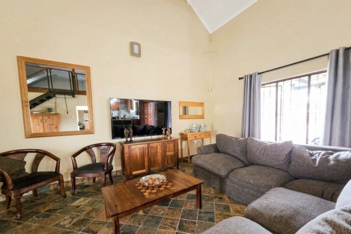 Spacious living room featuring high vaulted ceilings, natural stone tile flooring, and large windows allowing for ample natural light.