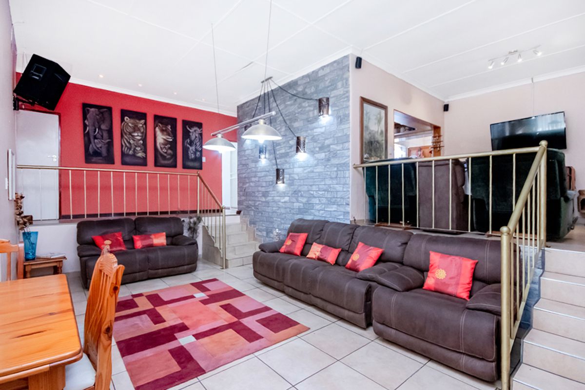 Split-level living area featuring a stone-clad feature wall, tiled flooring, and integrated metal railings connecting the different levels of the home.