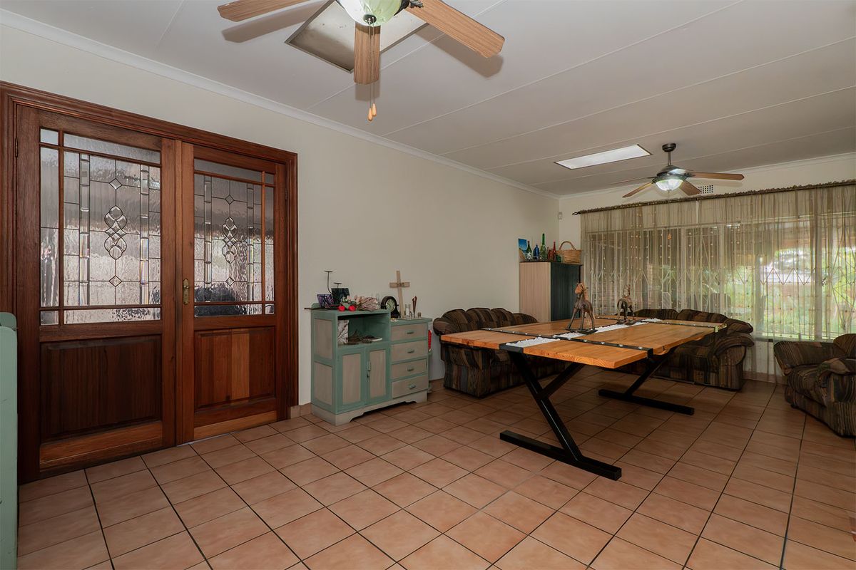 Spacious living area featuring tiled flooring, dual ceiling fans, a skylight for natural light, and elegant leaded glass double doors.