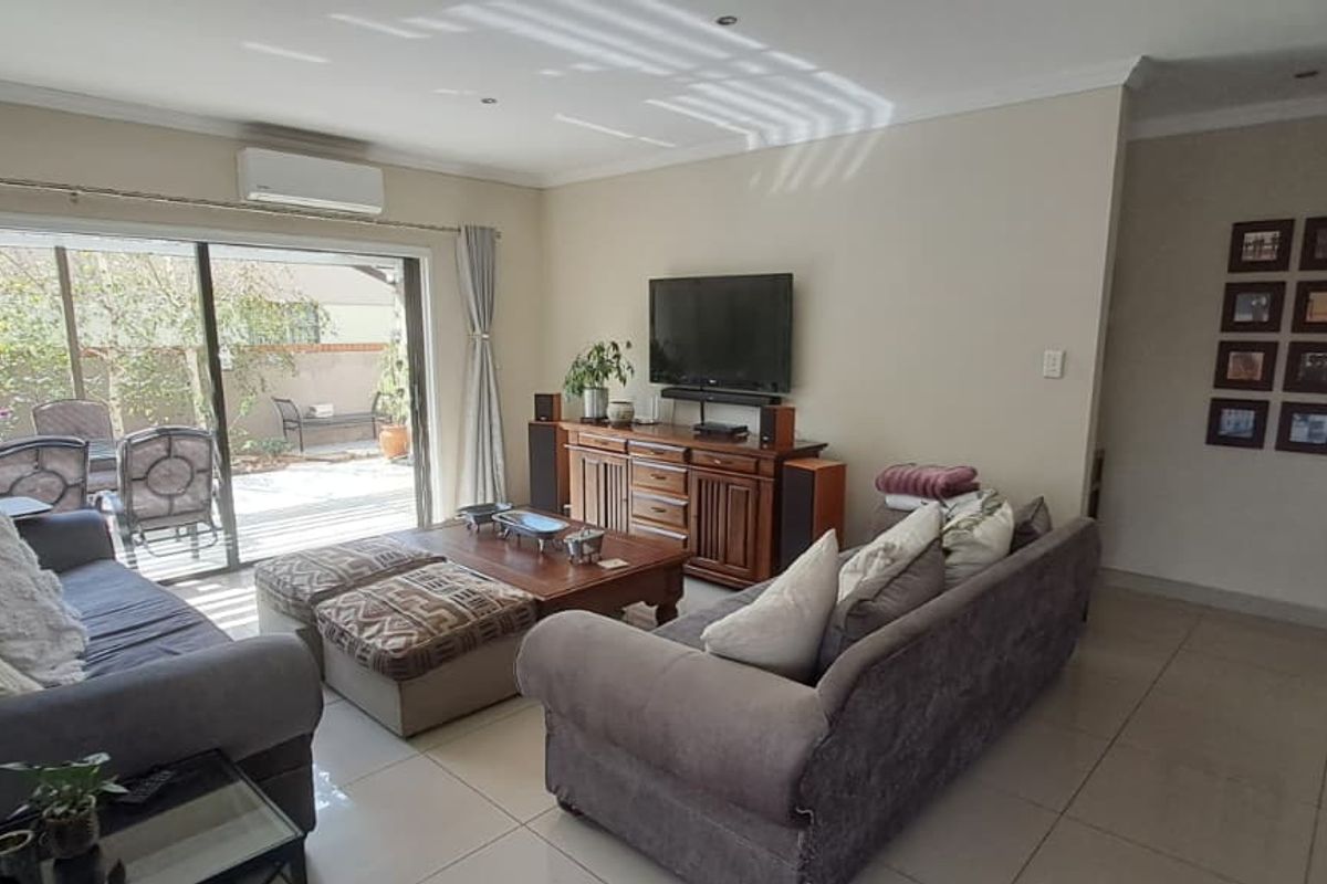 Spacious living area featuring large sliding glass doors that open onto a patio, tiled flooring, and a wall-mounted air conditioning unit.