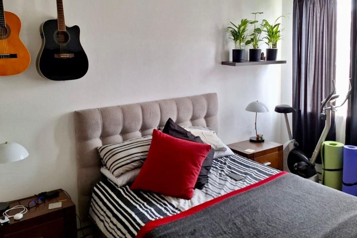 A bedroom featuring a neutral wall finish, window with dark curtains, and space for a double bed.