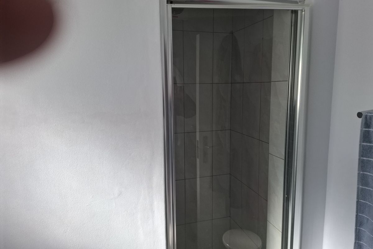 A compact shower enclosure featuring tiled walls and a glass door, integrated into the bathroom space.