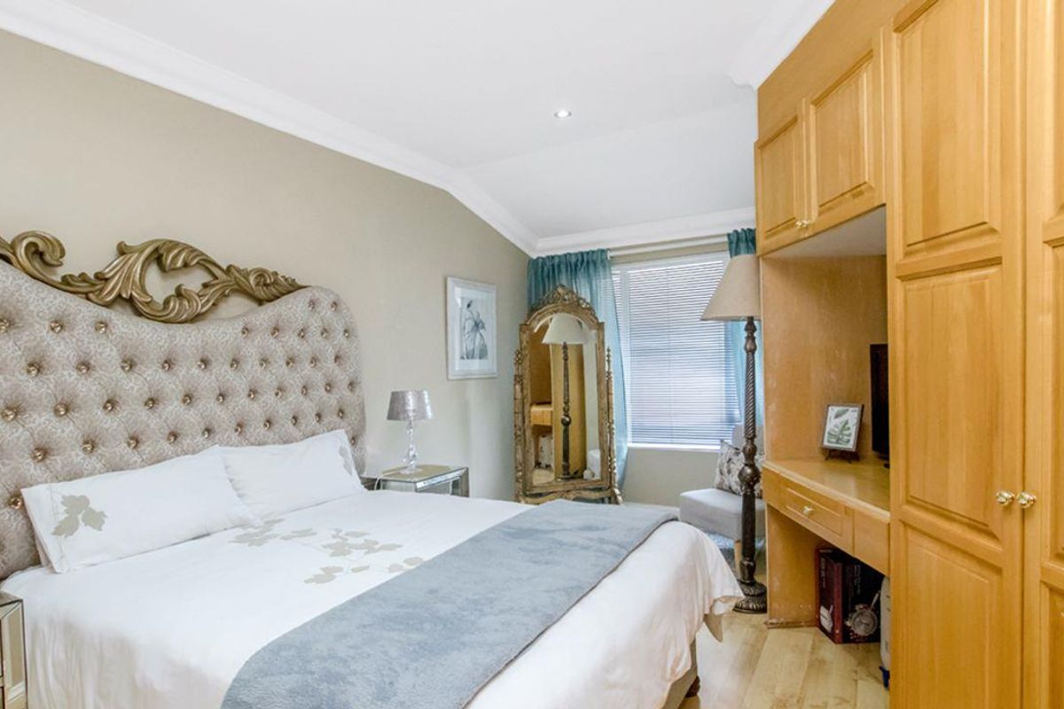 A well-lit bedroom featuring built-in wooden cabinetry, recessed ceiling lighting, and crown molding, providing ample storage and a classic aesthetic.