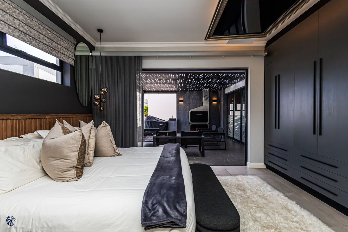 Modern bedroom featuring dark built-in cabinetry, crown molding, and large sliding glass doors opening onto a covered patio area.