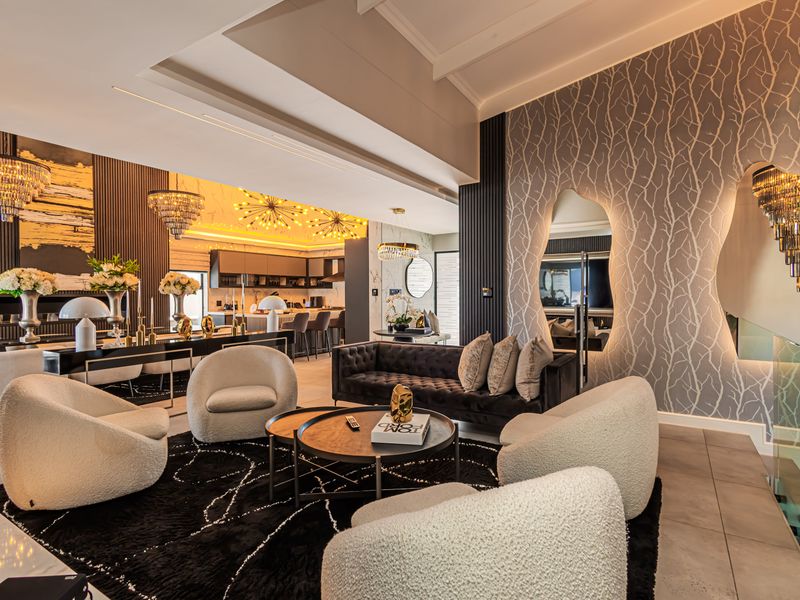 A sophisticated open-plan living and kitchen area featuring high-end finishes, modern lighting, feature wallpaper, and a seamless flow between the lounge and kitchen.