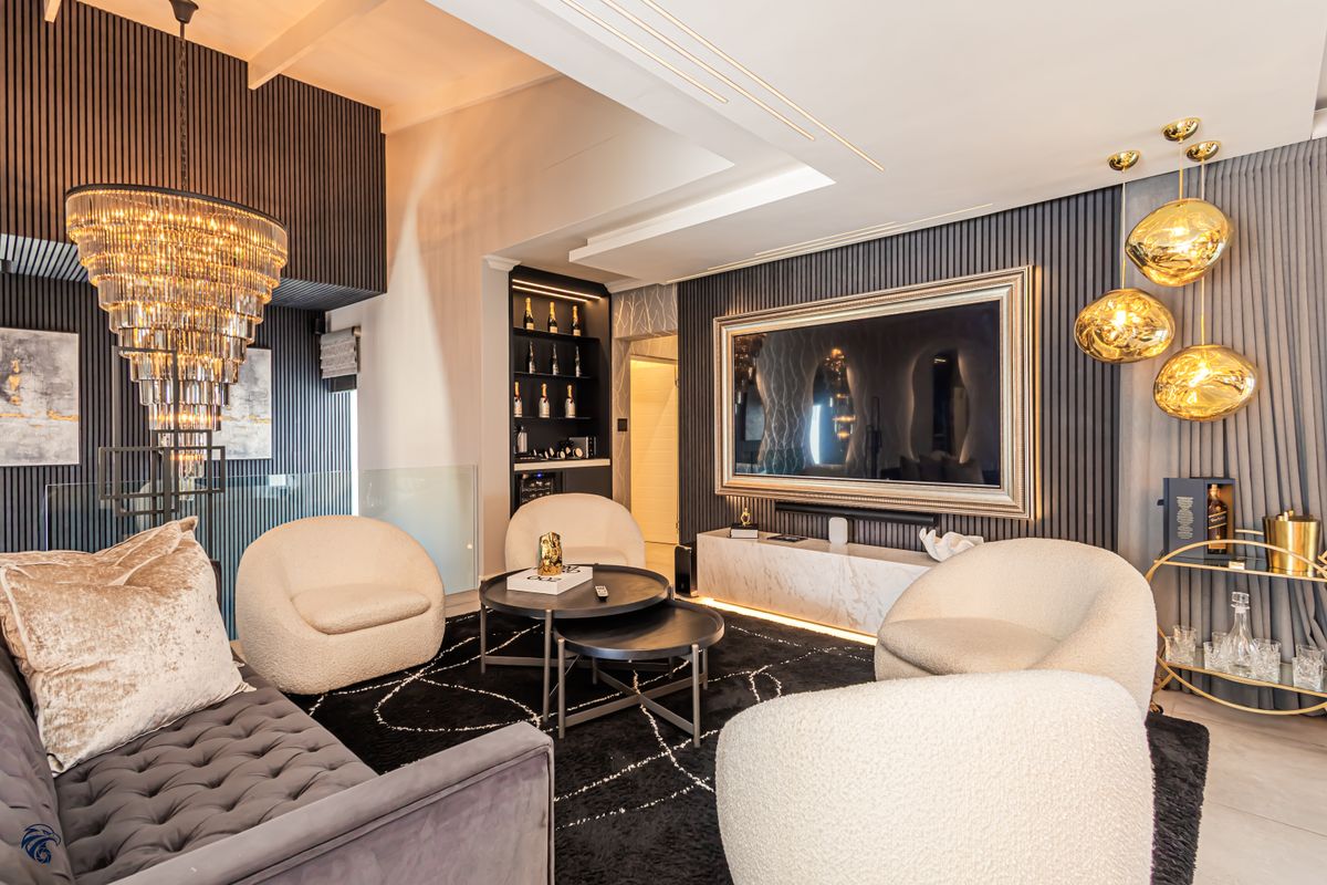 A sophisticated living room featuring dark slatted wall paneling, a marble media console, recessed ceiling lighting, and a striking crystal chandelier.