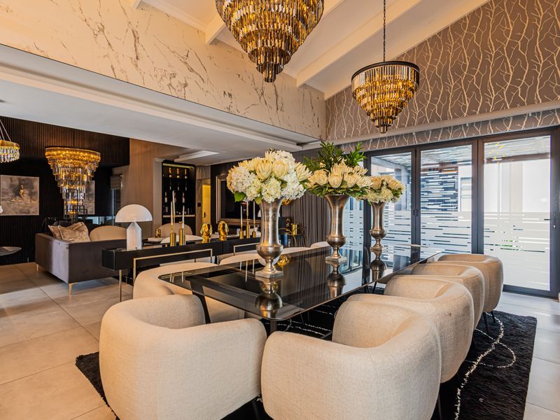 Luxurious open-plan living and dining area featuring vaulted ceilings, marble-effect wall accents, sophisticated wallpaper, and large aluminium sliding doors leading to the exterior.