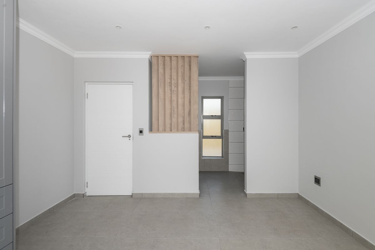 A clean, modern interior space featuring neutral grey floor tiles, a white internal door, and a decorative timber slat feature wall.