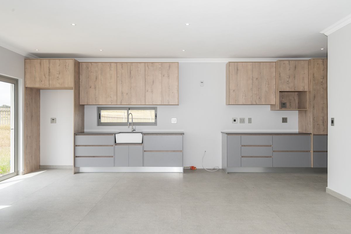 Modern kitchen featuring two-tone cabinetry, a farmhouse-style sink, and tiled flooring, offering a clean and functional layout.