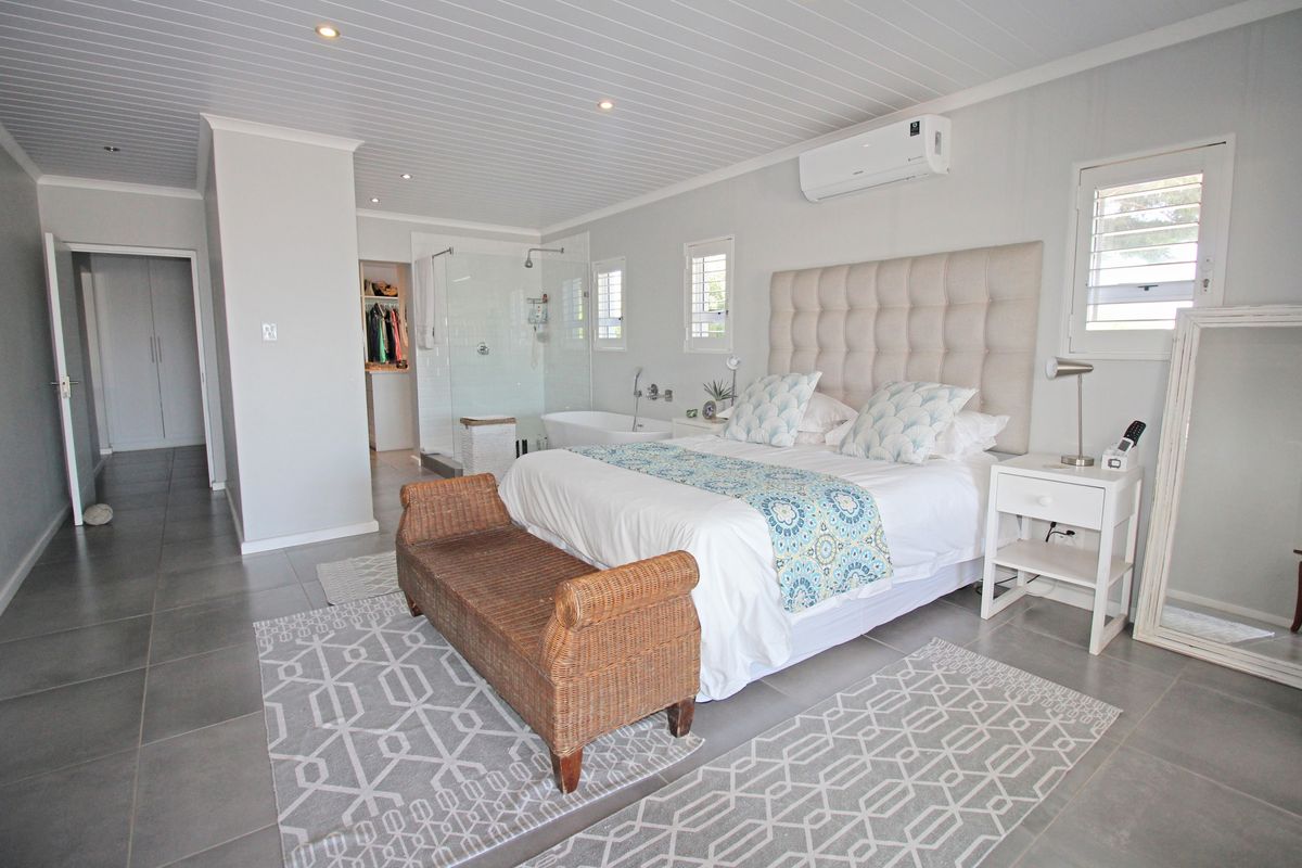 Spacious bedroom featuring a modern en-suite bathroom with a glass-enclosed shower and freestanding bathtub, complemented by tiled flooring and a split-system air conditioner.