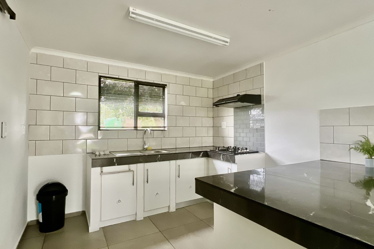 A functional kitchen featuring white cabinetry, dark stone countertops, subway tile backsplash, a built-in gas hob, and an extractor fan.