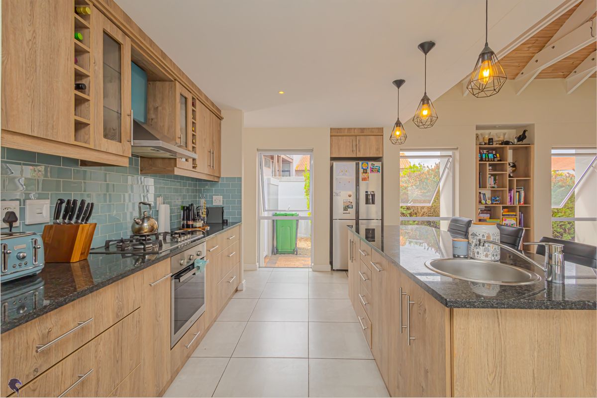 Modern kitchen featuring wood-look cabinetry, granite countertops, a central island with a prep sink, and a gas hob with an extractor fan.