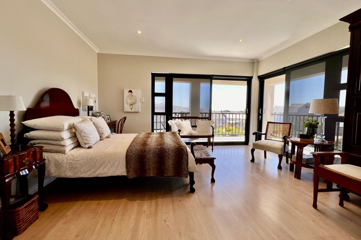 Spacious bedroom featuring light wood-look flooring, recessed downlighting, and large sliding glass doors opening onto a private balcony with scenic views.