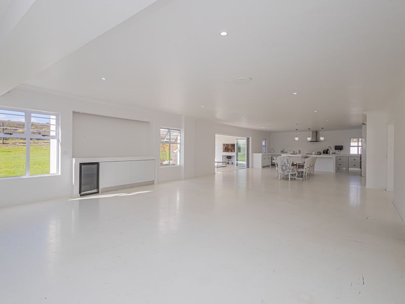 Spacious open-plan living and kitchen area featuring white flooring, recessed lighting, and a modern kitchen island with integrated appliances.