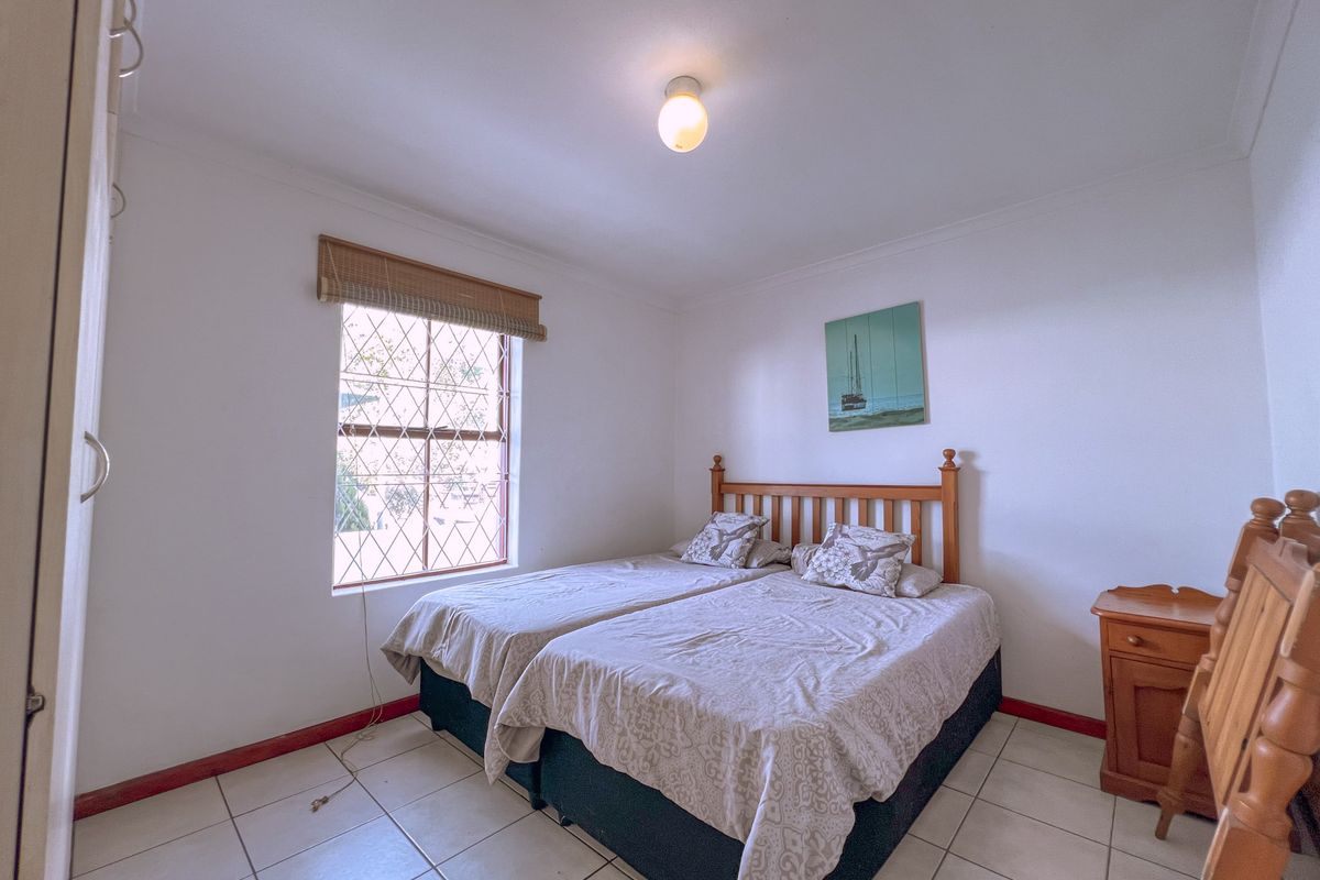 A bedroom featuring tiled flooring, a window with security bars, and built-in cupboard space.