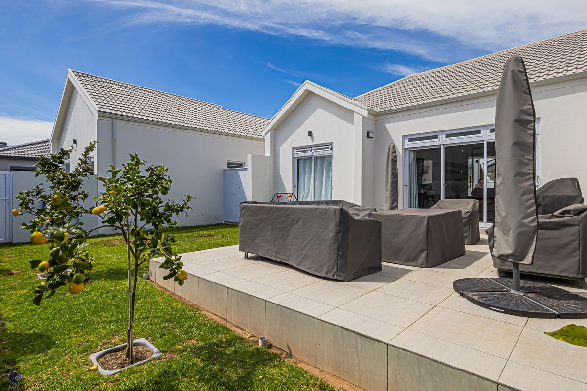 A well-maintained rear exterior view featuring a paved patio area, landscaped garden, and sliding glass doors providing access to the home's interior.