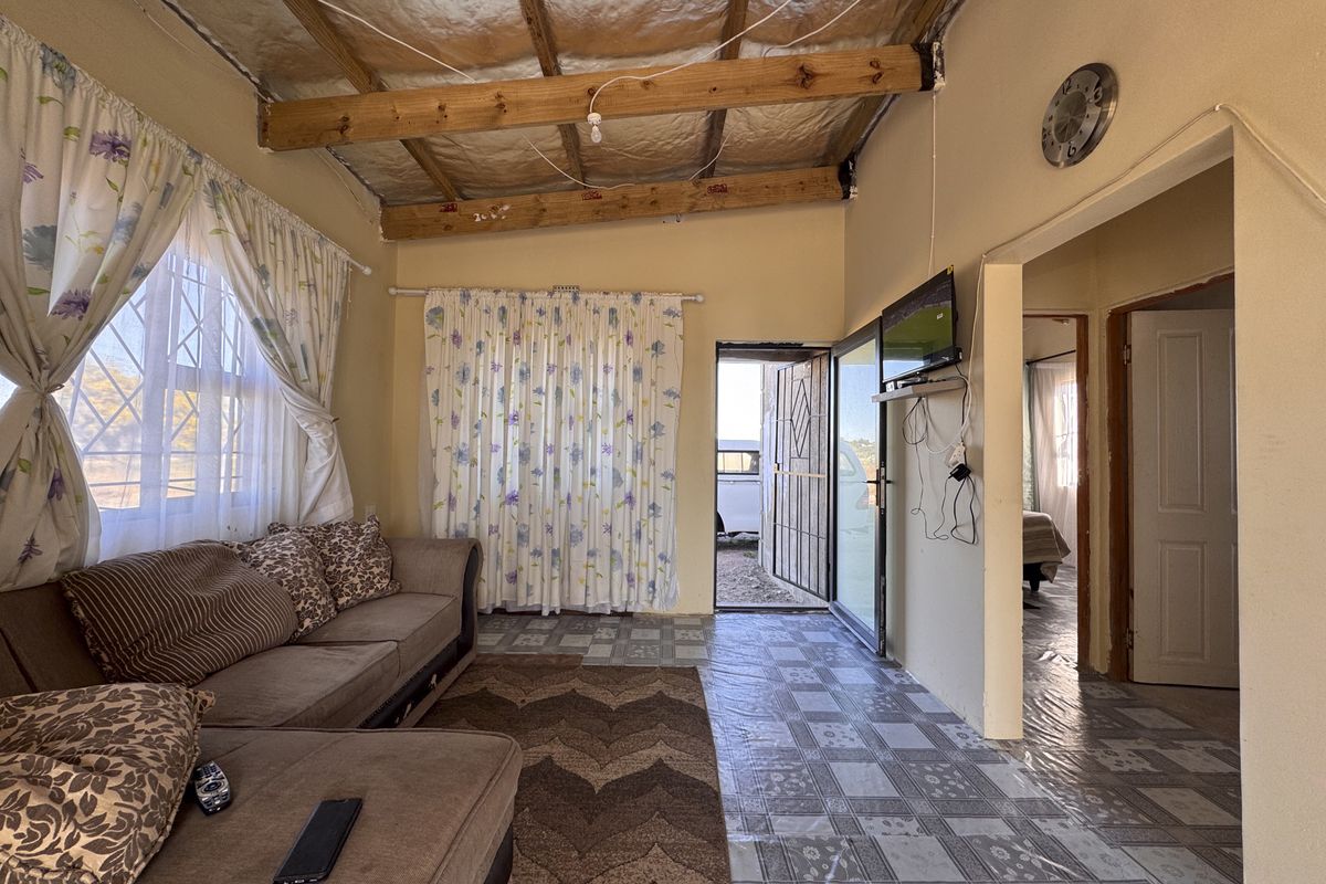 Living room featuring exposed timber roof beams, tiled flooring, and direct access to the exterior, providing a rustic farm-style living space.