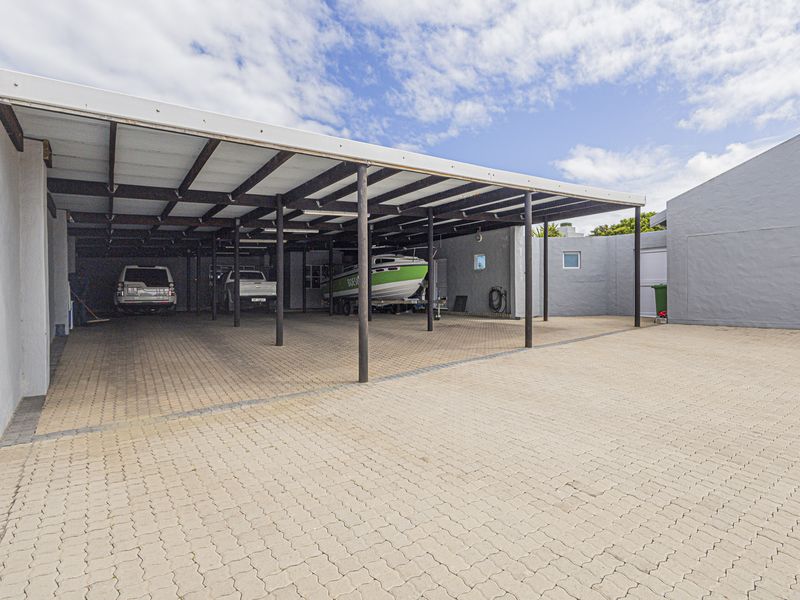 Spacious paved outdoor carport area providing ample covered parking space for multiple vehicles or recreational equipment.