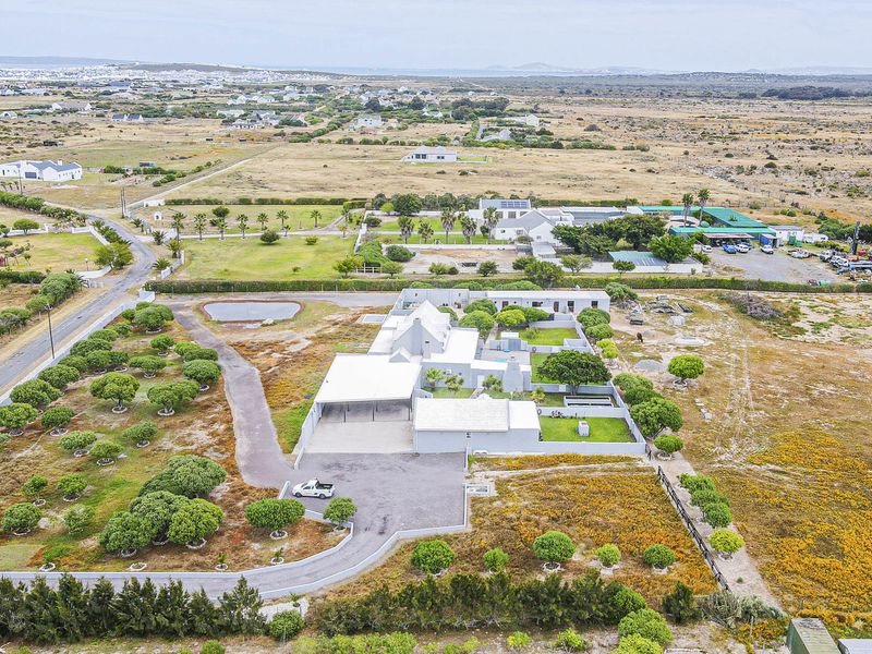 Aerial view of the property showcasing the main dwelling, expansive grounds, paved driveway, and surrounding landscape in a rural setting.
