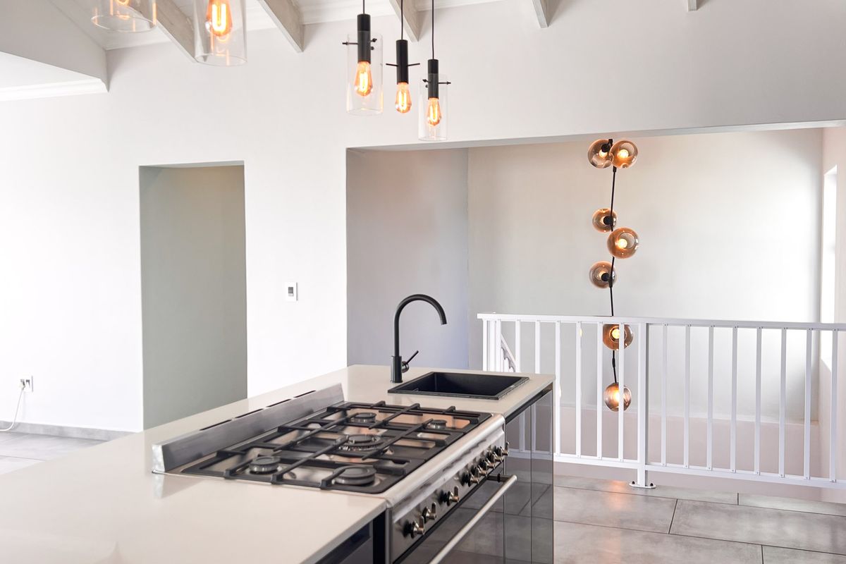 Modern kitchen featuring a central island with a built-in gas hob, oven, and integrated sink, complemented by contemporary pendant lighting and vaulted ceilings.