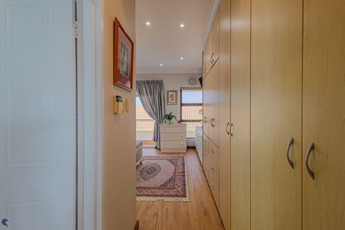 A well-maintained bedroom featuring extensive built-in cabinetry, laminate flooring, and natural light flowing from the adjacent balcony area.