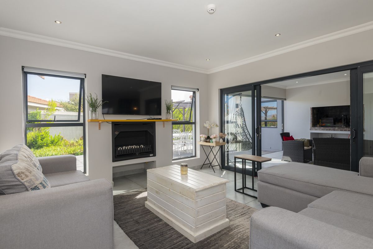 A bright and modern living room featuring a built-in fireplace, large windows, and sliding glass doors that open onto a covered patio area.