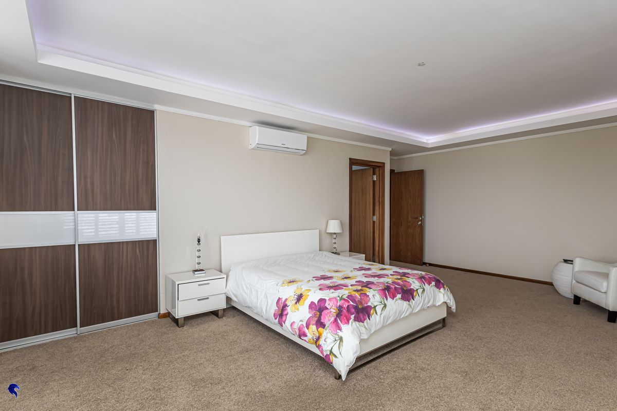 Spacious bedroom featuring a built-in sliding wardrobe, split-system air conditioning, and a modern tray ceiling with integrated ambient lighting.