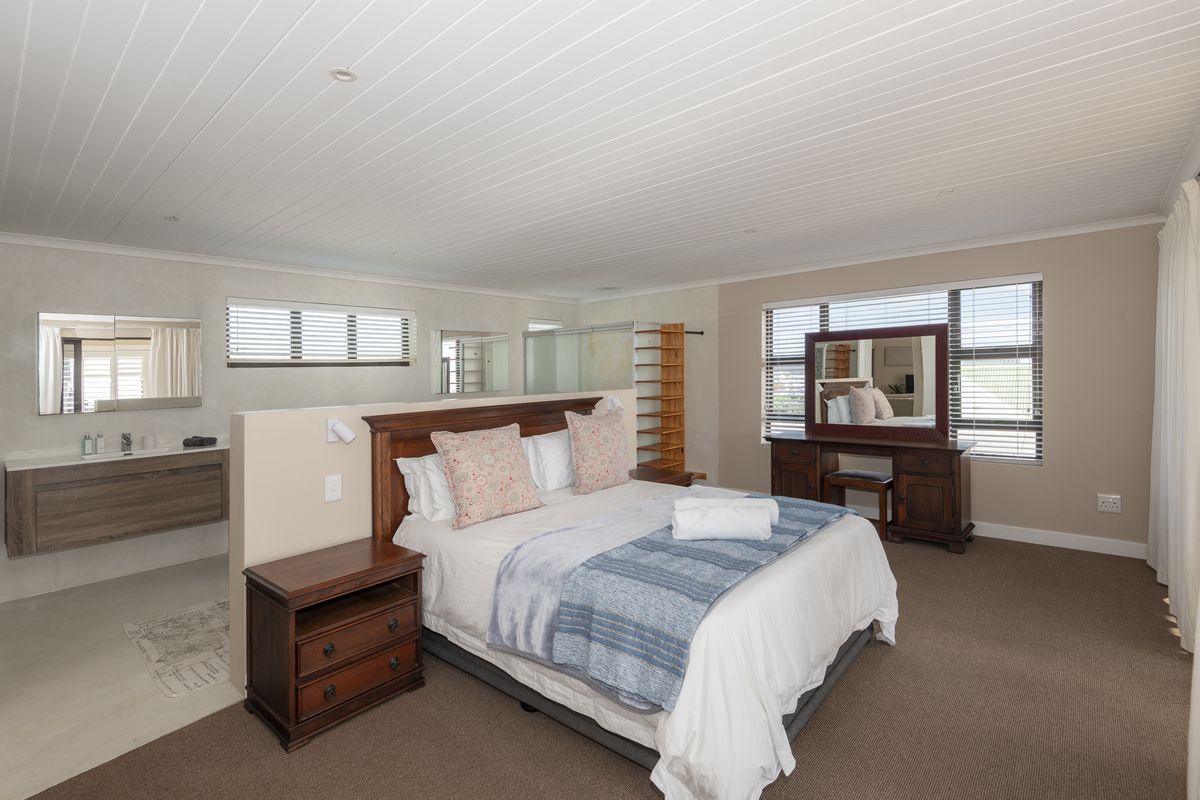 Spacious open-plan bedroom featuring a partition wall separating the sleeping area from a built-in vanity and en-suite bathroom section with modern finishes.