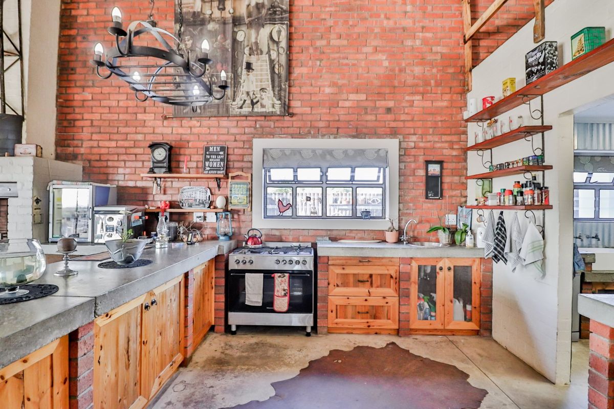 Rustic kitchen featuring exposed brick walls, concrete countertops, wooden cabinetry, and a gas stove, creating a warm, industrial-style culinary space.