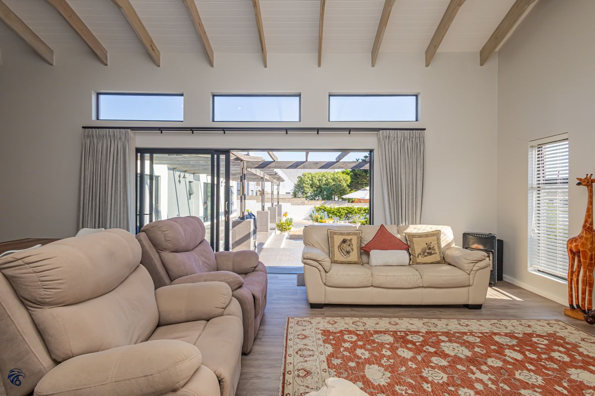 Spacious living room featuring high ceilings with exposed timber beams, clerestory windows, and large sliding doors opening to an outdoor patio area.