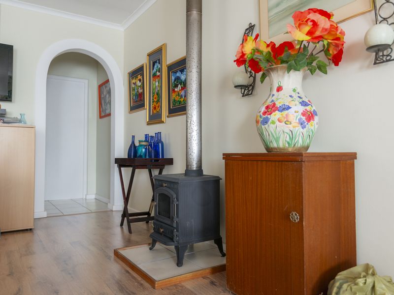 A living room featuring a cast iron wood burning stove with a flue pipe, set on a tiled hearth, with an arched doorway leading through.